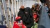 FILE - A Syrian woman caring a baby, walks with others to cross back to the border town of Tal Abyad in Syria from Turkey, at the border crossing in Akcakale, southeastern Turkey, June 17, 2015. 