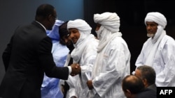 Le ministre malien des affaires étrangères Abdoulaye Diop (G) salue des représentants des groupes armés au terme d'une cérémonie de paix à Alger, le 1er mars 2015.