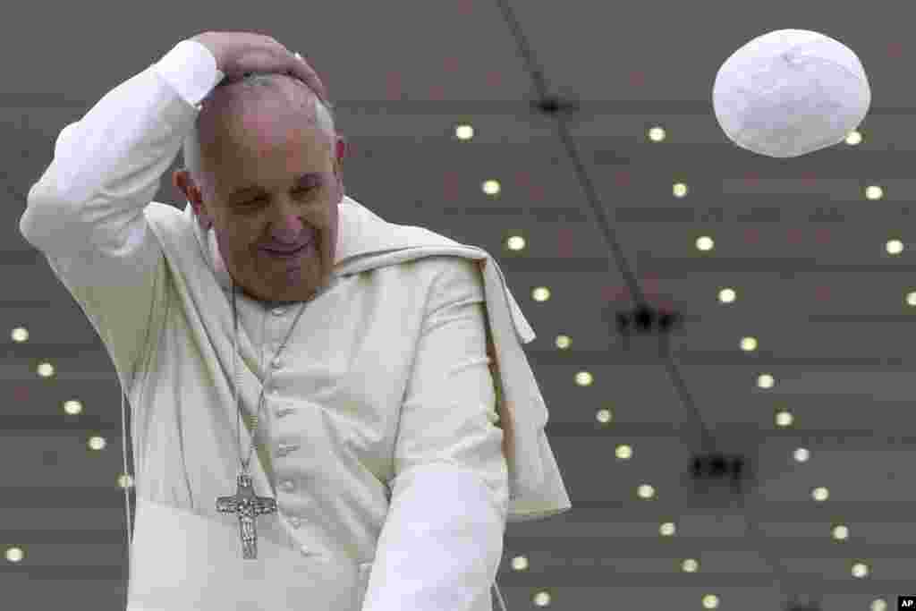 A gust of wind blows away Pope Francis' cap as he leaves at the end of his weekly general audience, at the Vatican.