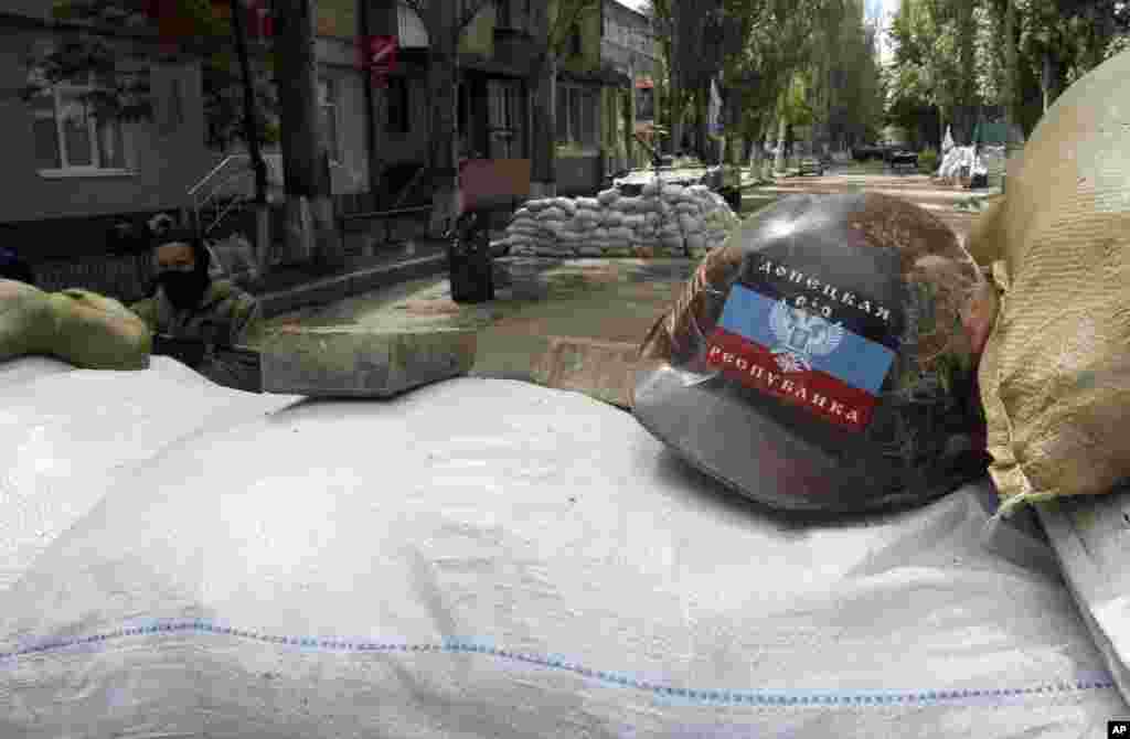 An armed pro-Russian man guards the local administration building behind barricades, with a helmet bearing a flag of the self-proclaimed Donetsk People's Republic, Slovyansk, May 6, 2014.