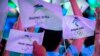 FILE - Participants wave flags with the logos of 2022 Beijing Winter Olympics and Paralympics before a launch ceremony to reveal the motto for the Winter Olympics and Paralympics in Beijing, Sept. 17, 2021. 