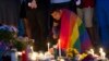 An unidentified man, wrapped in a rainbow flag, lights a candle during a vigil in Washington, June 13, 2016.