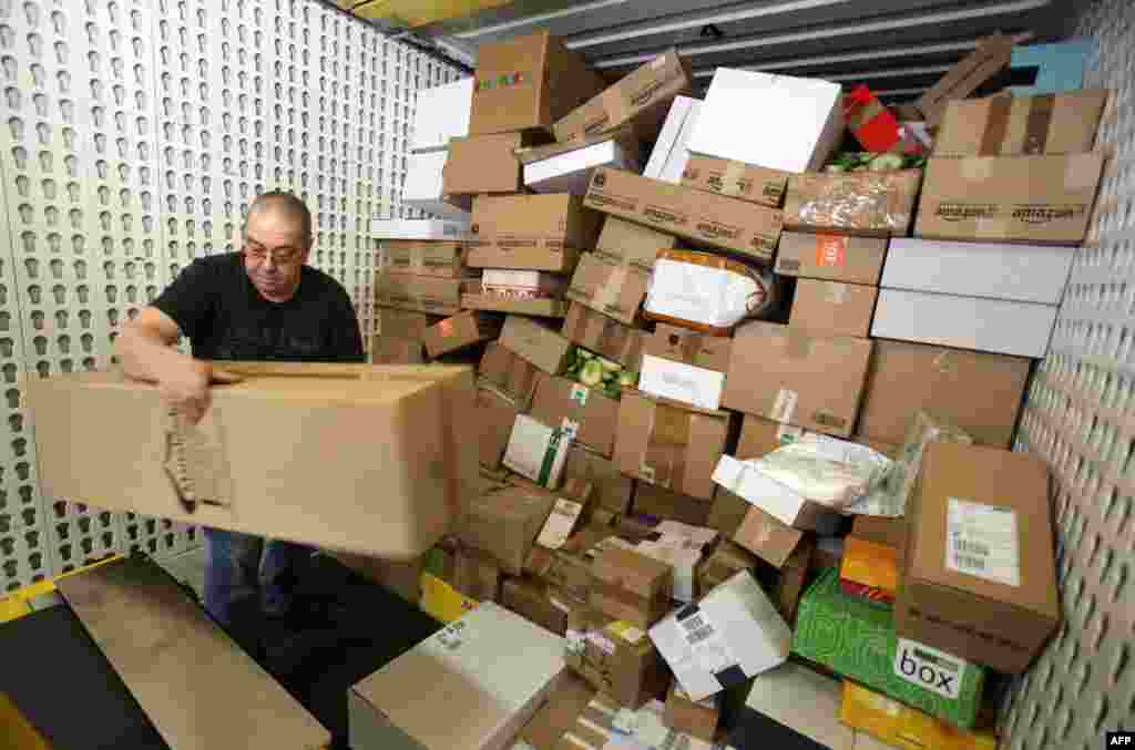 An employee of DHL, a division of German postal service Deutsche Post, unloads parcels from a transport vehicle at the company&#39;s logistics center in Gross Schwass near Rostock. During the pre-Christmas period, around 12,000 parcels per day are handled at the center, which is the double the usual amount, Dec. 18, 2013.