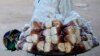 A boy sells bread near a court where youths play Eton fives game in a court in Katsina.