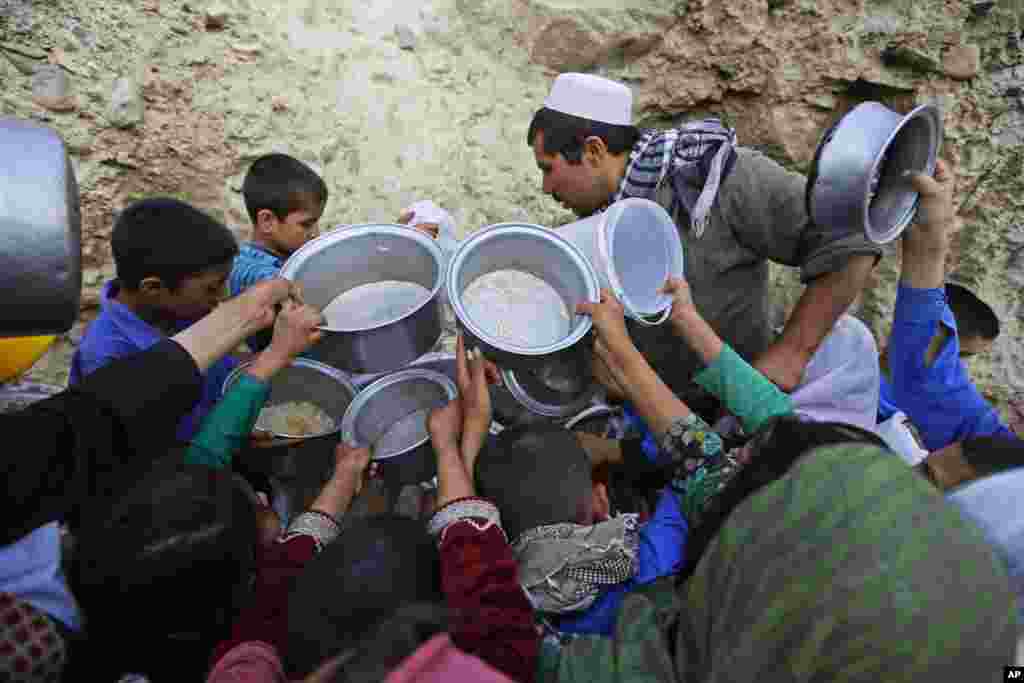 Warga desa Afghanistan berkumpul untuk menerima sumbangan makanan menjelang berbuka puasa Ramadan di Kabul.