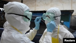 Les agents de santé portant des vêtements de protection se préparent à transporter un cadavre abandonné présentant des symptômes d'Ebola au marché Duwala à Monrovia, le 17 aout 2014.