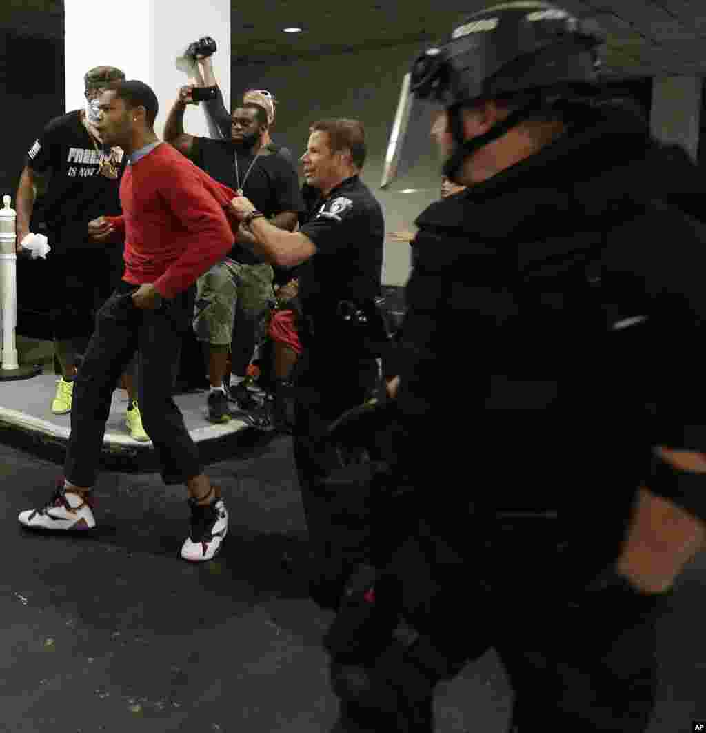 A man is detained by police during a protest of Tuesday's fatal police shooting of Keith Lamont Scott in Charlotte, N.C., Sept. 21, 2016. Protesters rushed police in riot gear at a downtown Charlotte hotel and officers have fired tear gas to disperse the