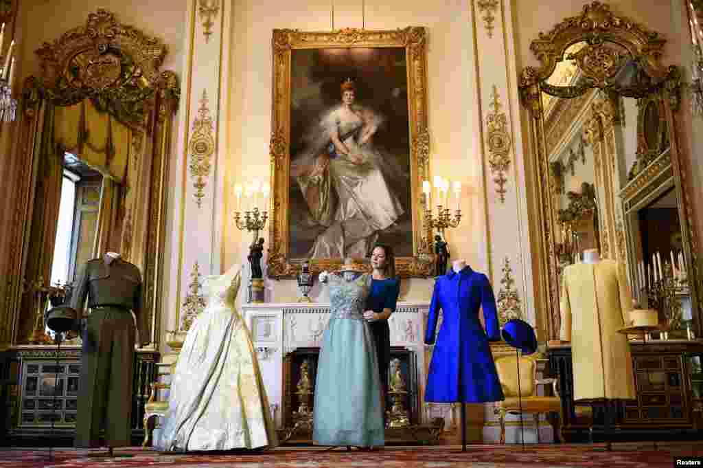 Curator Caroline de Guitaut shows off a preview of an exhibition entitled &#39;Fashioning a Reign: 90 Years of Style from The Queen&#39;s Wardrobe,&#39; charting the reign of Britain&#39;s Queen Elizabeth via a display of her formal and informal outfits, at Buckingham Palace, in central London.