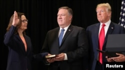 Gina Haspel jure sur la Bible tenue par Mike Pompeo, le secrétaire d'état. Elle est la nouvelle directrice de la CIA. A droite, le président américain Donald Trump assiste à la cérémonie à Langley, le siege de la CIA, le 21 mai 2018. 