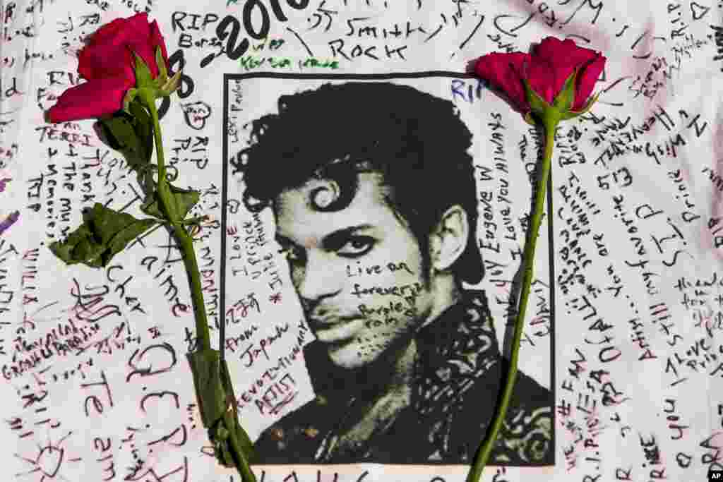 Flowers lay on a T-shirt signed by fans of singer Prince at a makeshift memorial place created outside Apollo Theatre in New York, April 22, 2016. The pop star died at the age of 57.