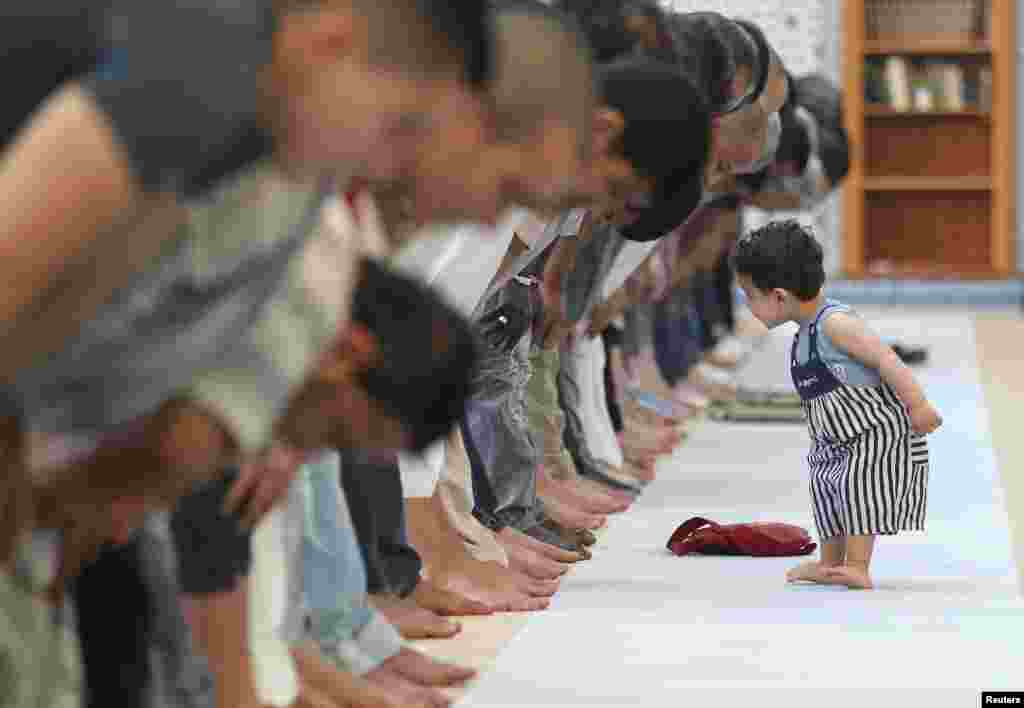 A child walks near members of the Muslim community attending midday prayers at Strasbourg Grand Mosque in Strasbourg, France, on the first day of Ramadan.