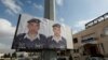 FILE - Two posters with pictures of Jordanian pilot Lt. Muath al-Kaseasbeh hang on a street pole, in front of the pilot's tribal gathering place, in Amman, Jordan,