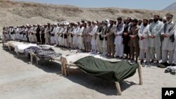 Afghan men offer funeral prayers near the bodies of 7 civilians killed, by a roadside bomb in the Alingar district of Laghman province, east of Kabul, Afghanistan, June 03, 2013.