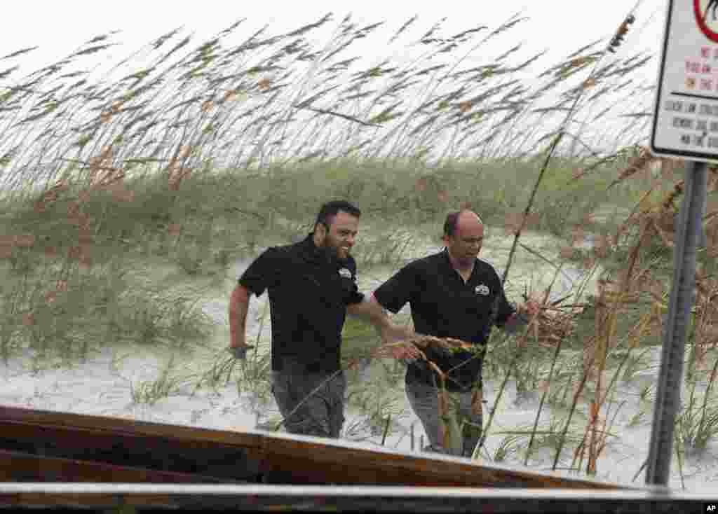Two men run for cover as rain ahead of Hurricane Matthew begins to fall October 6, 2016, in Jacksonville Beach, Florida. Hurricane Matthew steamed toward heavily populated Florida Thursday, and 2 million people across the Southeast were warned to flee in