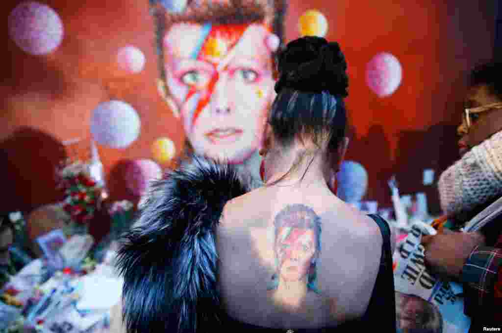 A woman with a Ziggy Stardust tattoo visits a mural of David Bowie in Brixton, south London, Jan. 11, 2016. The music legend, who used daringly androgynous displays of sexuality and glittering costumes to frame legendary rock hits &quot;Ziggy Stardust&quot; and &quot;Space Oddity&quot;, died of cancer.&nbsp;