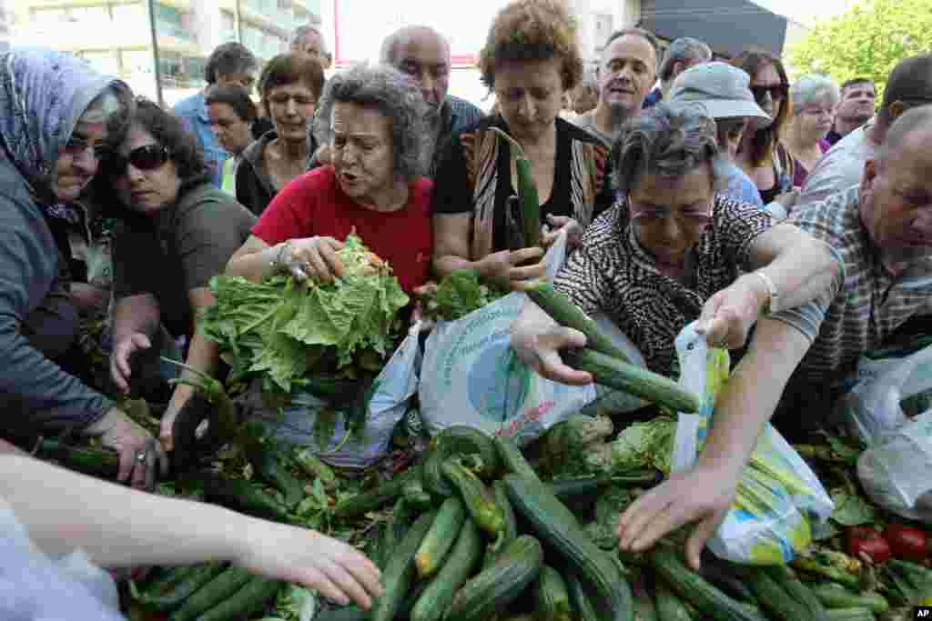 Orang-orang berebut mengambil sayuran dan buah segar yang didistribusikan oleh pedagang pasar sayur Yunani selama protes di Athena. Para pedagang Yunani melakukan protes dan membagikan produk segar kepada kerumunan massa. 