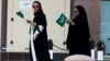 FILE - Saudi women hold national flags as they walk on a street during Saudi National Day in Riyadh, Saudi Arabia.