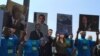 FILE - Metro Industrial Areas Foundation held up photos of five executives of top gun manufacturers, asking President Obama to pressure them. They want their distribution channels released, gun dealers who sell to criminals punished, and more smart technology for guns. (C. Presutti/VOA)