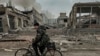 FILE - A man rides on a bike in front of the mail office which was destroyed by a Russian airstrike in Kurakhove, Donetsk region, Ukraine, on Nov. 7, 2024.