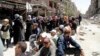 FILE - Residents wait to receive food aid distributed by the U.N. refugee agency at the Palestinian refugee camp of Yarmouk, south of Damascus, Syria, May 2014.