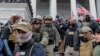 FILE - Jessica Watkins, second from left, and Donovan Crowl, center, both from Ohio, march down the east front steps of the U.S. Capitol with the Oath Keepers militia group among supporters of President Donald Trump in Washington, Jan. 6, 2021.