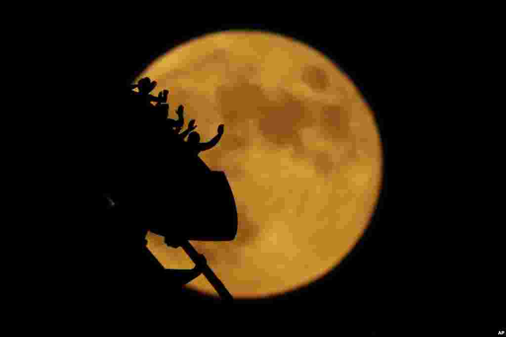 The full moon rises silhouetting roller coaster riders at the Worlds of Fun amusement park on the 50th anniversary of the Apollo 11 moon launch, in Kansas City, Missouri, July 16, 2019.