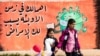 FILE Syrian children cross a road in front of a COVID-19 mural calling on people to take care during the pandemic in Syria's northeastern city of Qamishli, March 9, 2021..