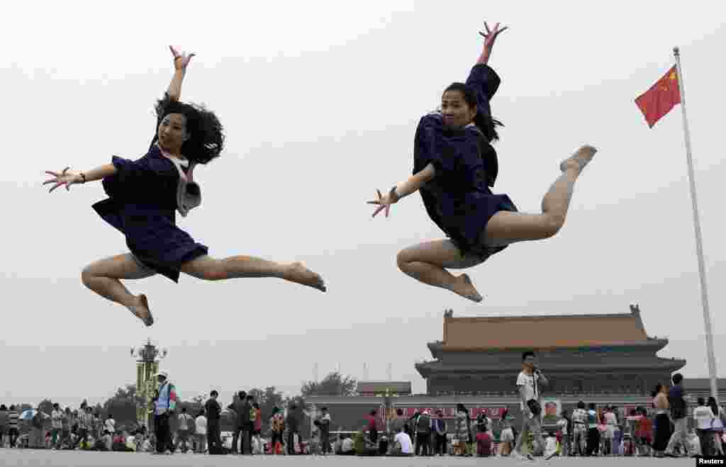 Graduates jump as they pose for photographs in front of the Tiananmen Gate and the giant portrait of late Chinese Chairman Mao Zedong, on the Tiananmen Square in Beijing, June 19, 2014.