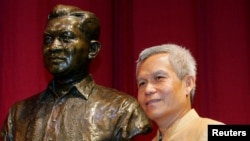 Sombath Somphone, aktivis sosial Laos, penerima penghargaan Ramon Magsaysay untuk Kepemimpinan Komunitas tahun 2005, berpose bersama patung mendiang presiden Filipina di Pusat Kebudayaan Filipina di Manila (Foto: dok). Somphone terakhir terlihat di ibukota Vientiane, saat kendaraannya dihentikan oleh pihak berwenang di luar sebuah kantor polisi, Sabtu (15/12). Pemerintah Laos membantah ikut bertanggung jawab atas hilangnya Somphone.