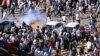 Demonstrators run from teargas lobbed to disperse them as they march along the street during anti-government protests in Khartoum, Sudan, Dec. 25, 2018. 