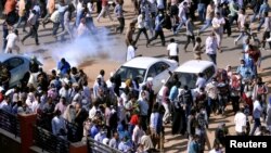 Demonstrators run from teargas lobbed to disperse them as they march along the street during anti-government protests in Khartoum, Sudan, Dec. 25, 2018. 