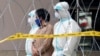 FILE - Police officers wearing protective suits pick up an illegal immigrant from an apartment under enhanced lockdown, in Kuala Lumpur, Malaysia, May 1, 2020.
