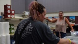 Magalia resident Natalie Fox, left, who is still displaced after the Camp Fire destroyed her home, picks up supplies from the church's distribution center. Volunteer Cathy Muncy, right, also lost her home in the fire. (Elizabeth Lee/VOA News)