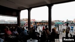 Des touristes sont assis dans un café de la place Jamaa Lafna à Marrakech, Maroc, le 15 mars 2020. REUTERS / Youssef Boudlal
