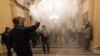 FILE - In this Jan. 6, 2021, file photo, smoke fills the walkway outside the Senate Chamber as violent rioters loyal to President Donald Trump are confronted by U.S. Capitol Police officers inside the Capitol in Washington. 