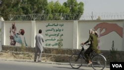 د خوست یو اوسېدونکي د ښار په لويديځه څنډه کې، پر يوه ديوال د رسم شوي عکس او لیکلي پیغام ننداره کوي.
