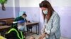 A voter, mask-clad due to the coronavirus pandemic, dips her finger in ink after voting at a polling station in Jordan's capital Amman, Nov. 10, 2020.