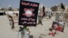 FILE - Religious flags, photographs and tributes to 21 victims of a suicide bombing of a Shi'ite mosque are displayed at a cemetery in al-Qudeeh, Saudi Arabia, May 30, 2015.