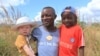 Razik Jaffalie porte ses deux fils à Machinga, au nord-est de Blantyre, au Malawi le 23 mai 2016. Il a dû abandonner son travail pour les protéger. 