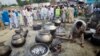 FILE - A Pakistani non-governmental humanitarian organization volunteer (front) adjusts a cooking fire as locals line up to receive meals in Nowshera, in Pakistan's northwest Khyber-Pakhtunkhwa Province, Sept. 10, 2010. Foreign-funded local organizations in northwestern Pakistan provide humanitarian and emergency assistance, including health, education, and food distribution, to more than two million people who have been displaced by ongoing Pakistani military operations against militant groups.